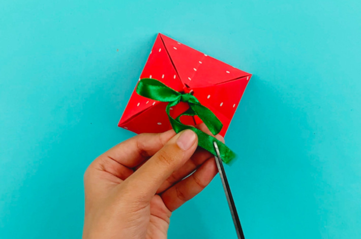 Two hands cutting off the excess ribbon.