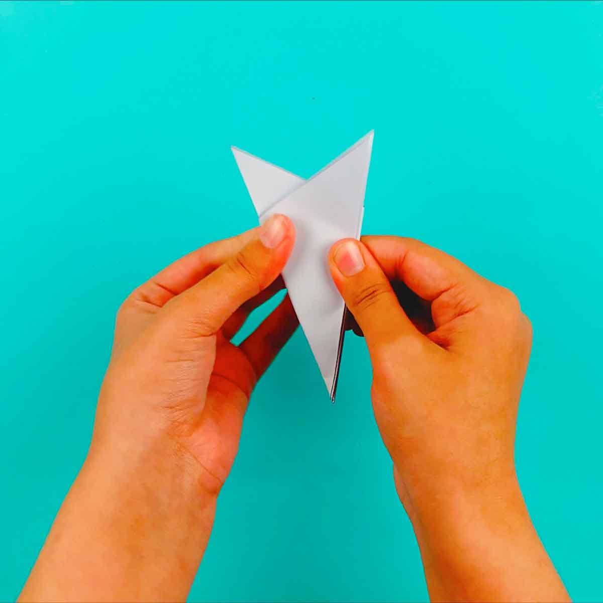 folded paper reach to be cut into a paper snowflake