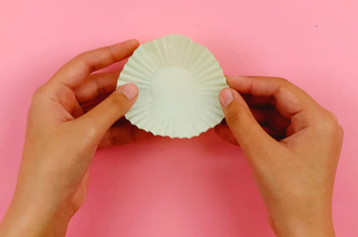 Two hands holding a green cupcake liner.