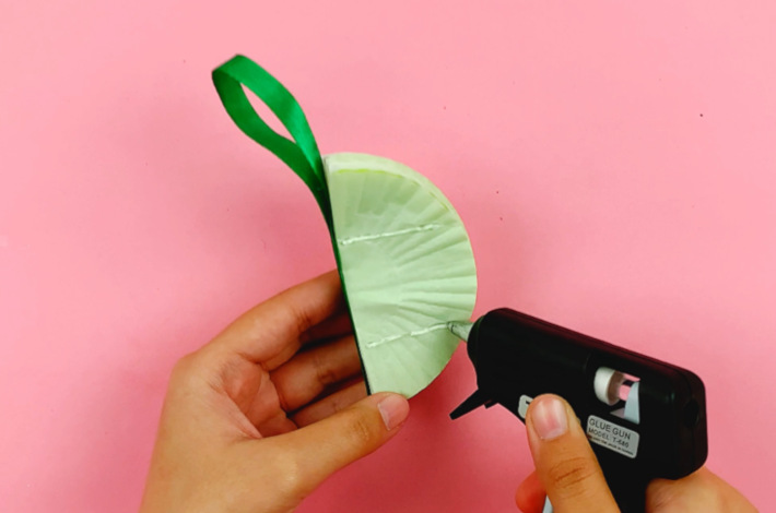Two hands applying glue to the facing cupcake liner.