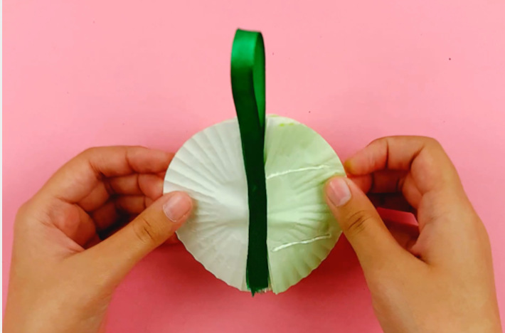 Two hands folding the back section around to form a circle and attaching together.