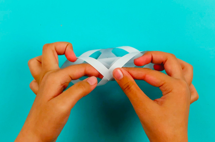 Two hands glueing the final piece of paper. 