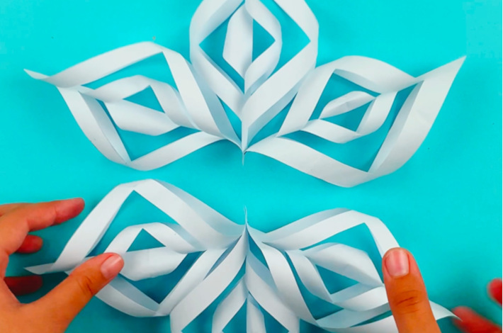 Two hands bringing the bottom section of the snowflake up to the top section.