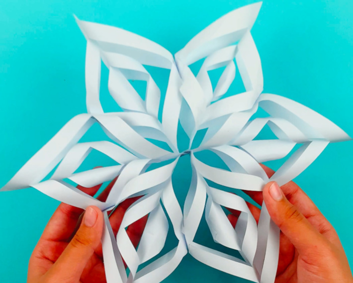 Two hands holding a completed 3D paper snowflake. 