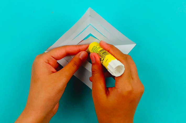 Two hands adding glue to the center triangles.