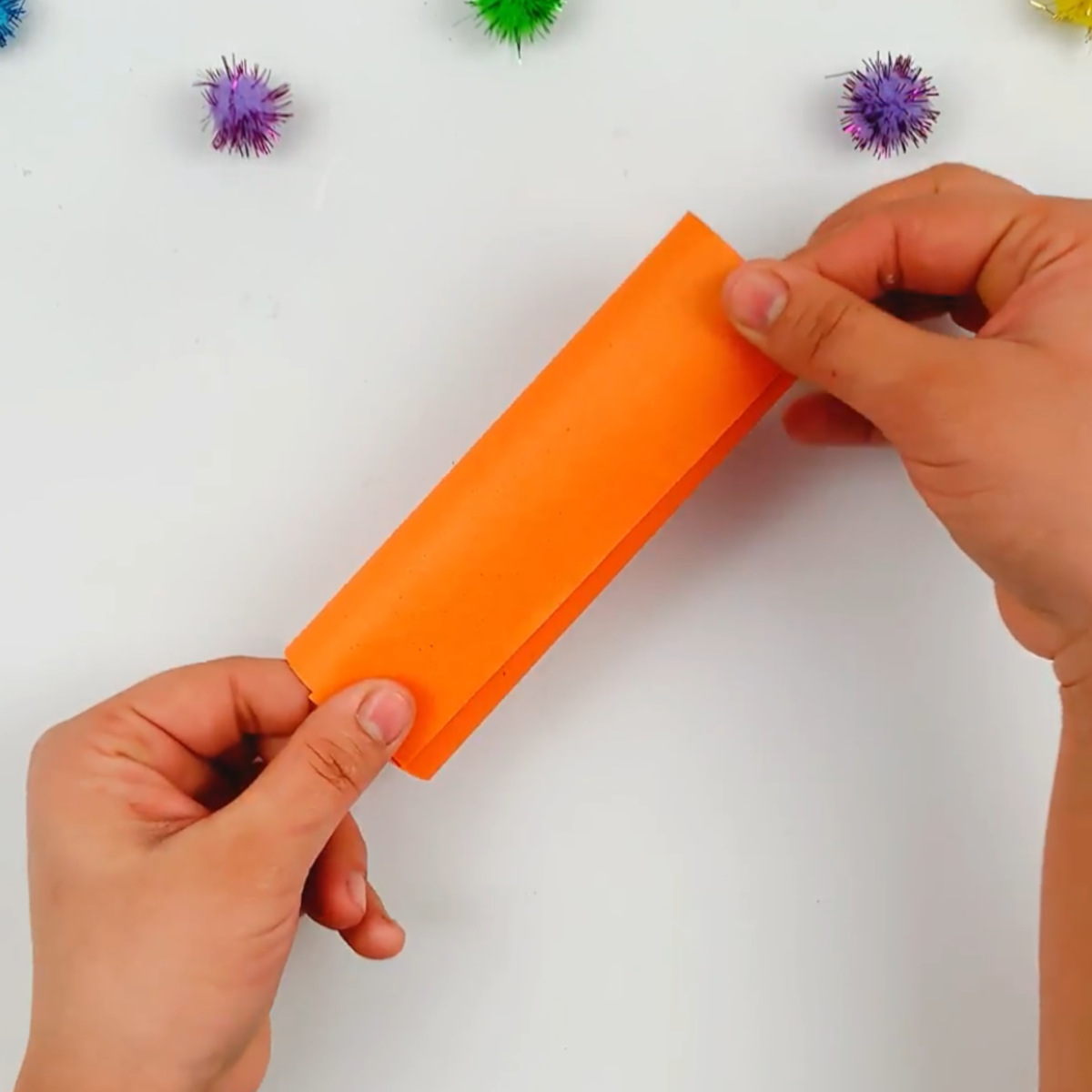 Two hands sticking the left-hand side to the glued area to form a cylinder.