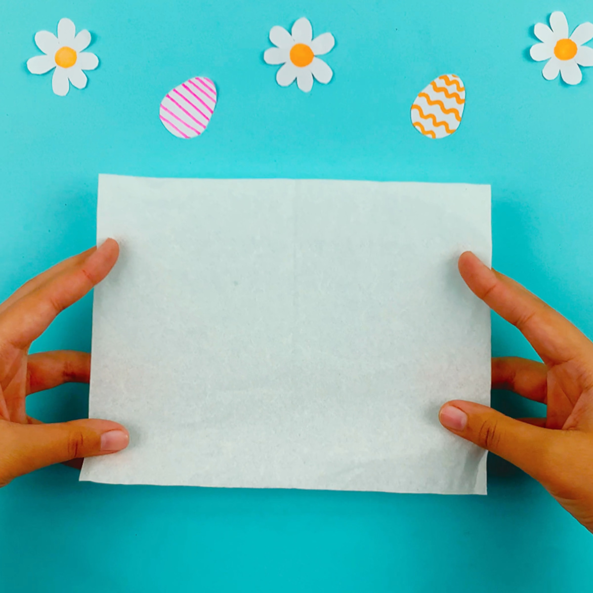 Two hands holding a regular tissue, ready to fold.