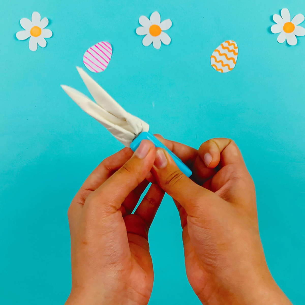 Two hands forming the tissue around into a circle and securing the bottom to sections with a staple.