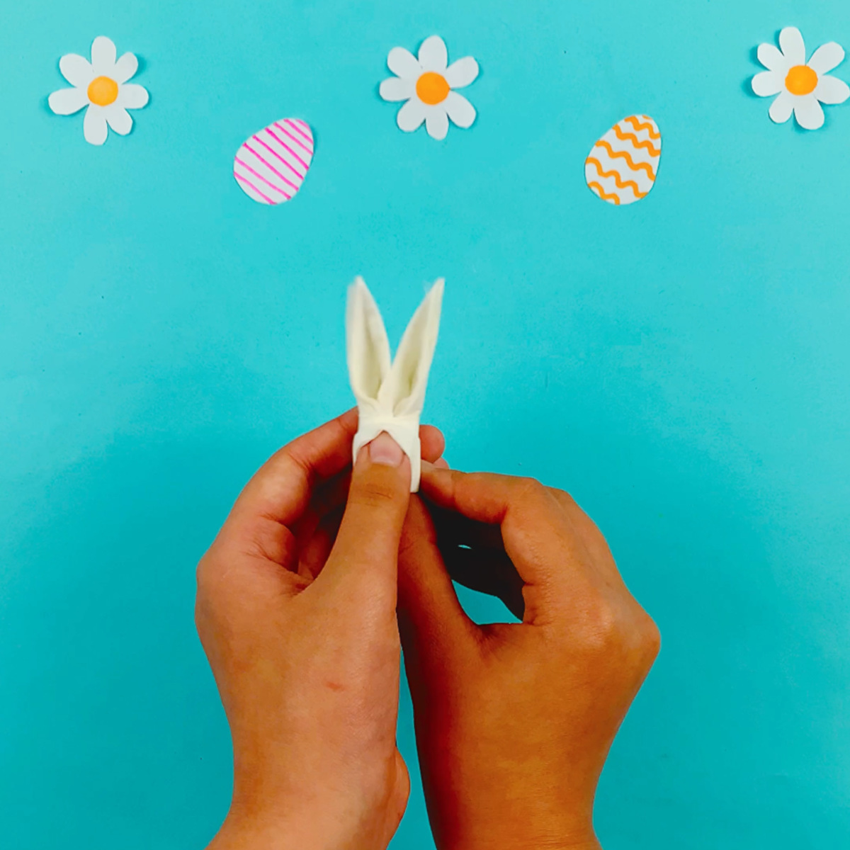 Two hands opening up the ears and the face area of the tissue.