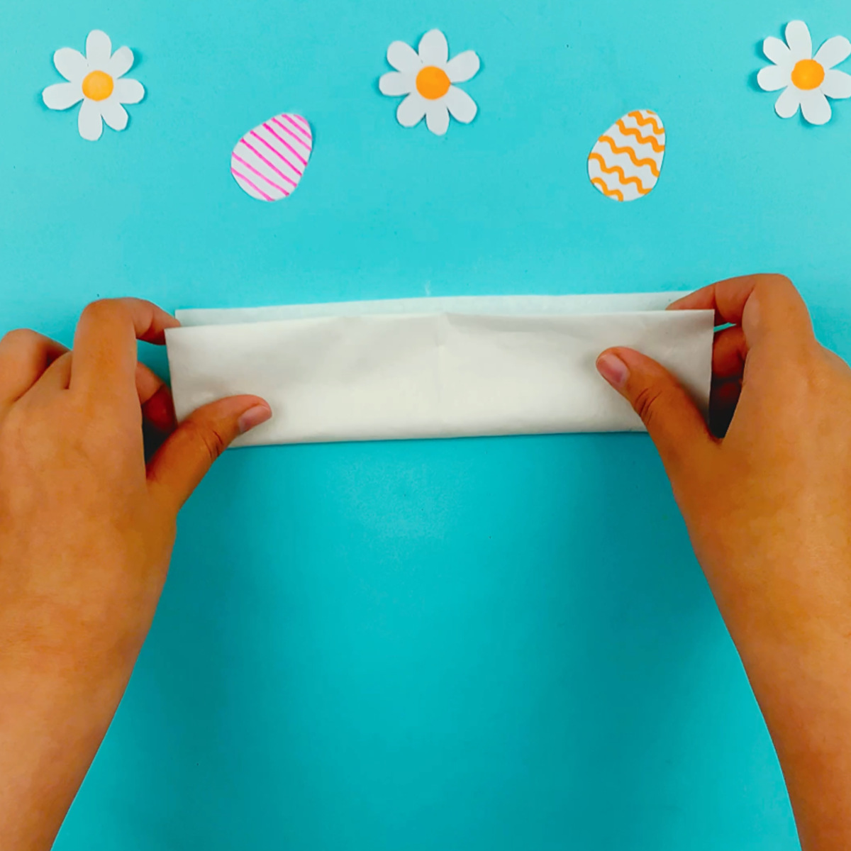 Two hands folding the bottom of the paper upwards again to form a rectangle.