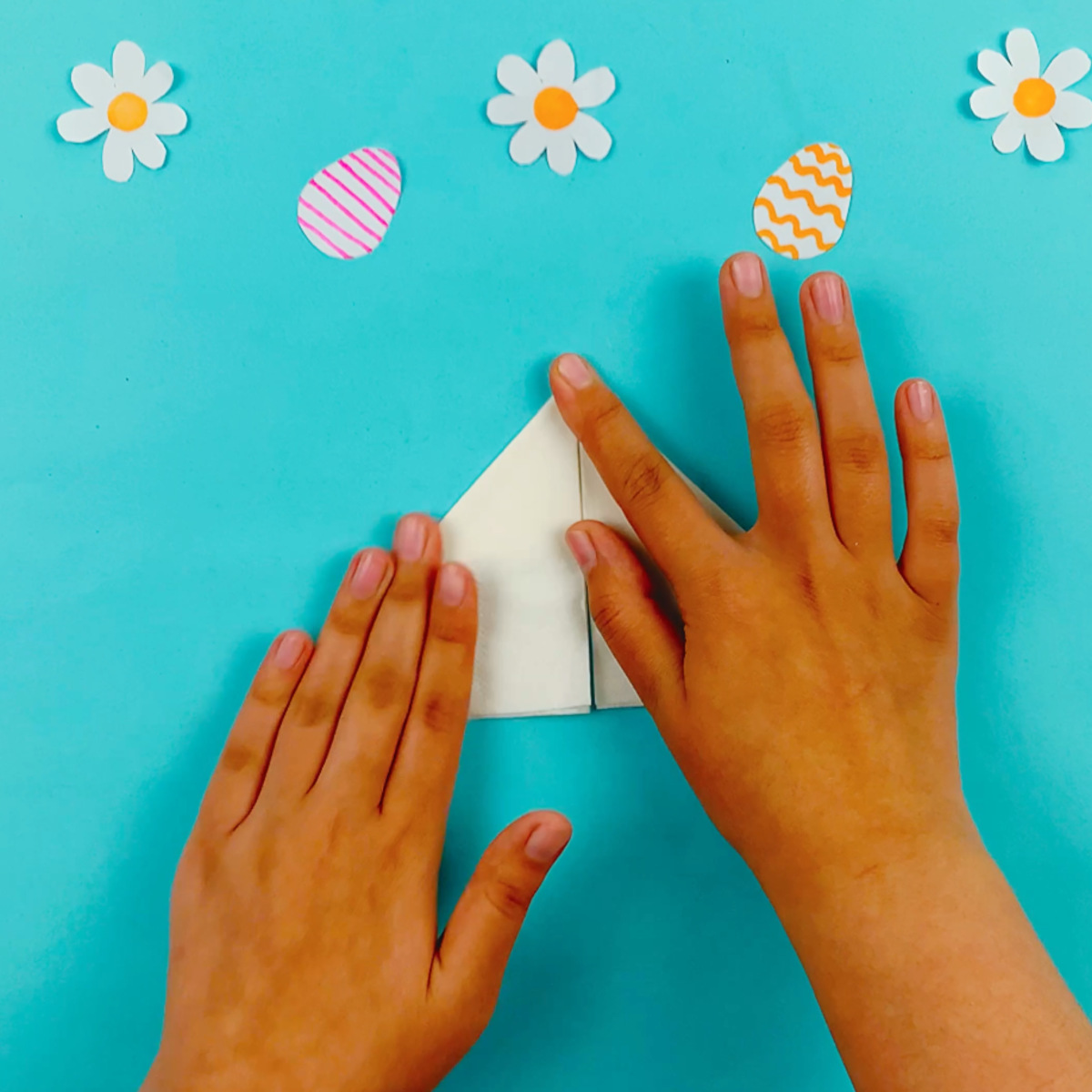 Two hands folding the right hand side downwards at a 45-degree angle.