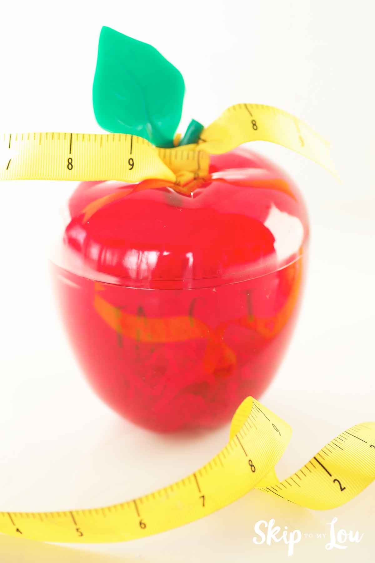 plastic apple with measuring tape ribbon tied to leaf