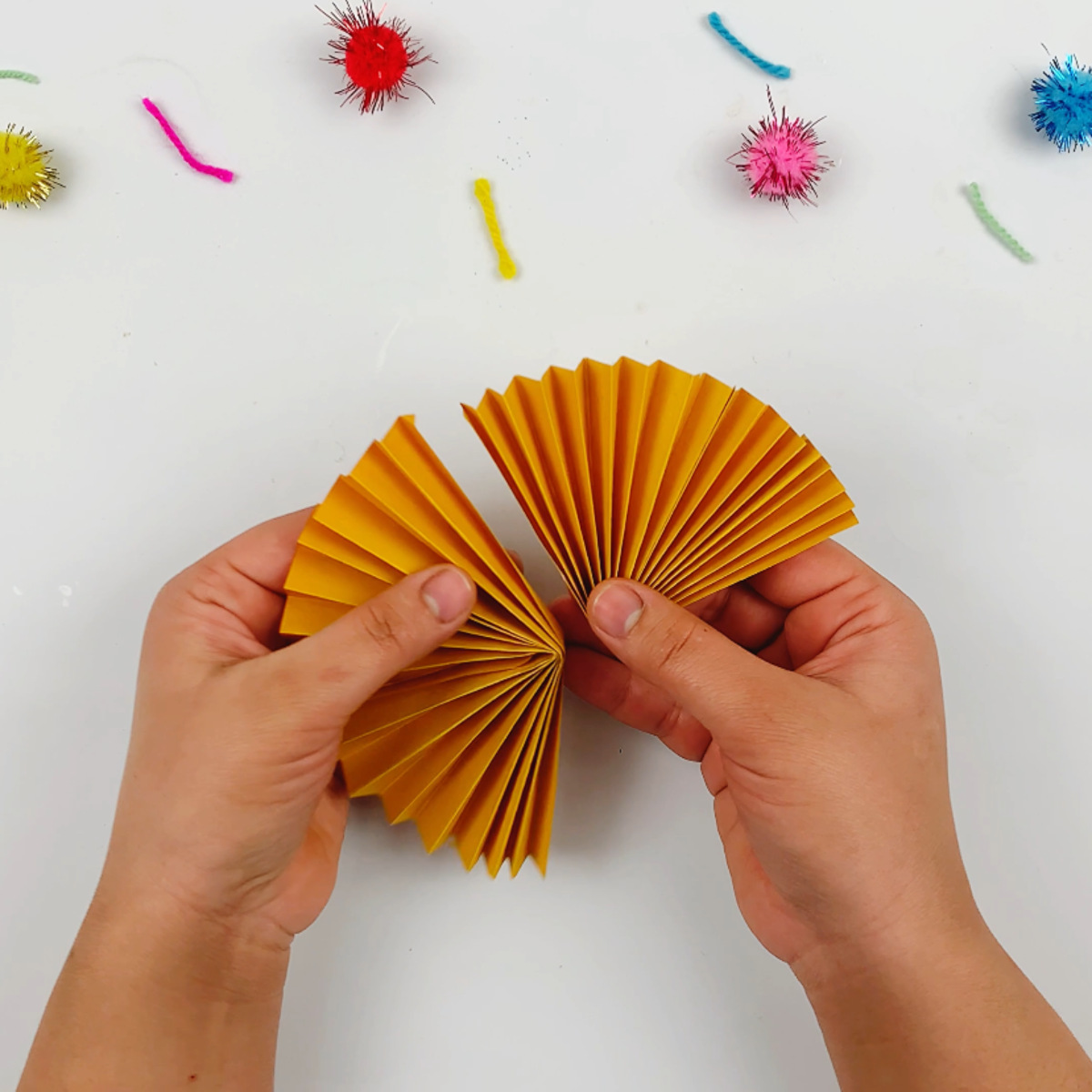 Two hands sticking two accordion flower petals together.
