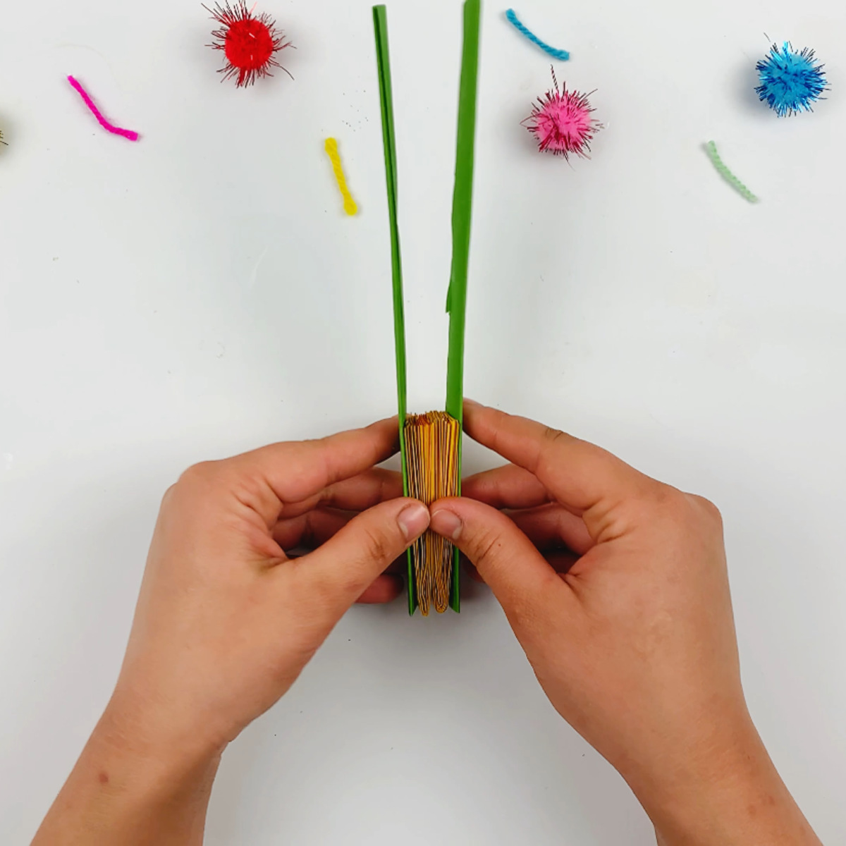 Two hands sticking the stems to the left and right side of the petals, pointing upwards. 