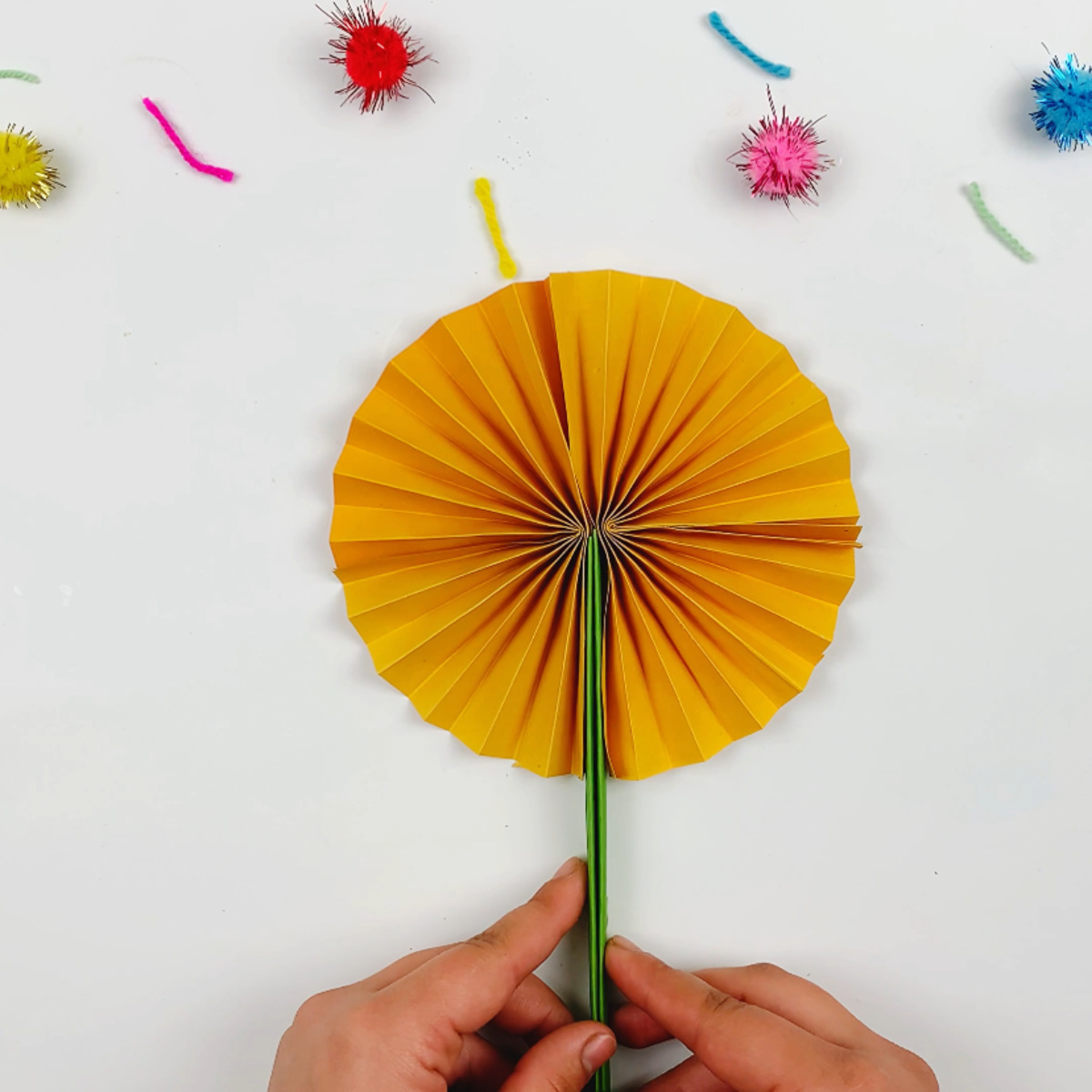 Two hands folding the stems downwards to form the flower. 
