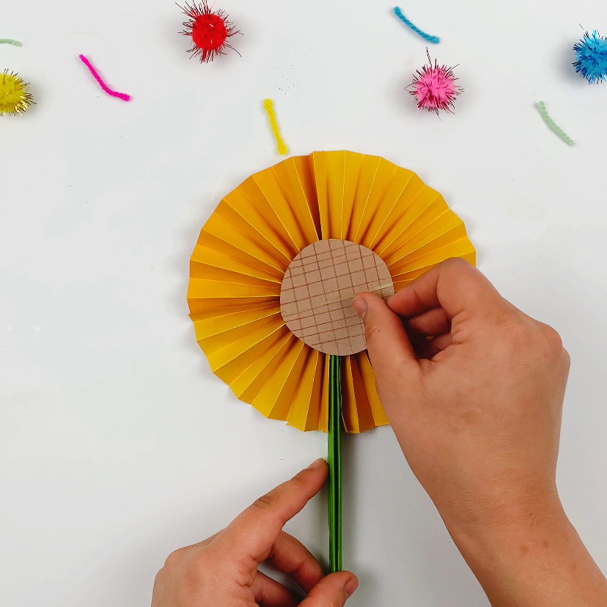 Two hands adding a center section to the accordion petal flower. 