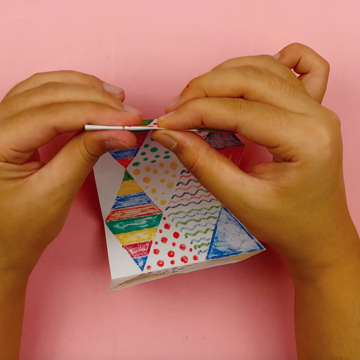 Two hands folding the flextangle after scoring along the dotted lines.