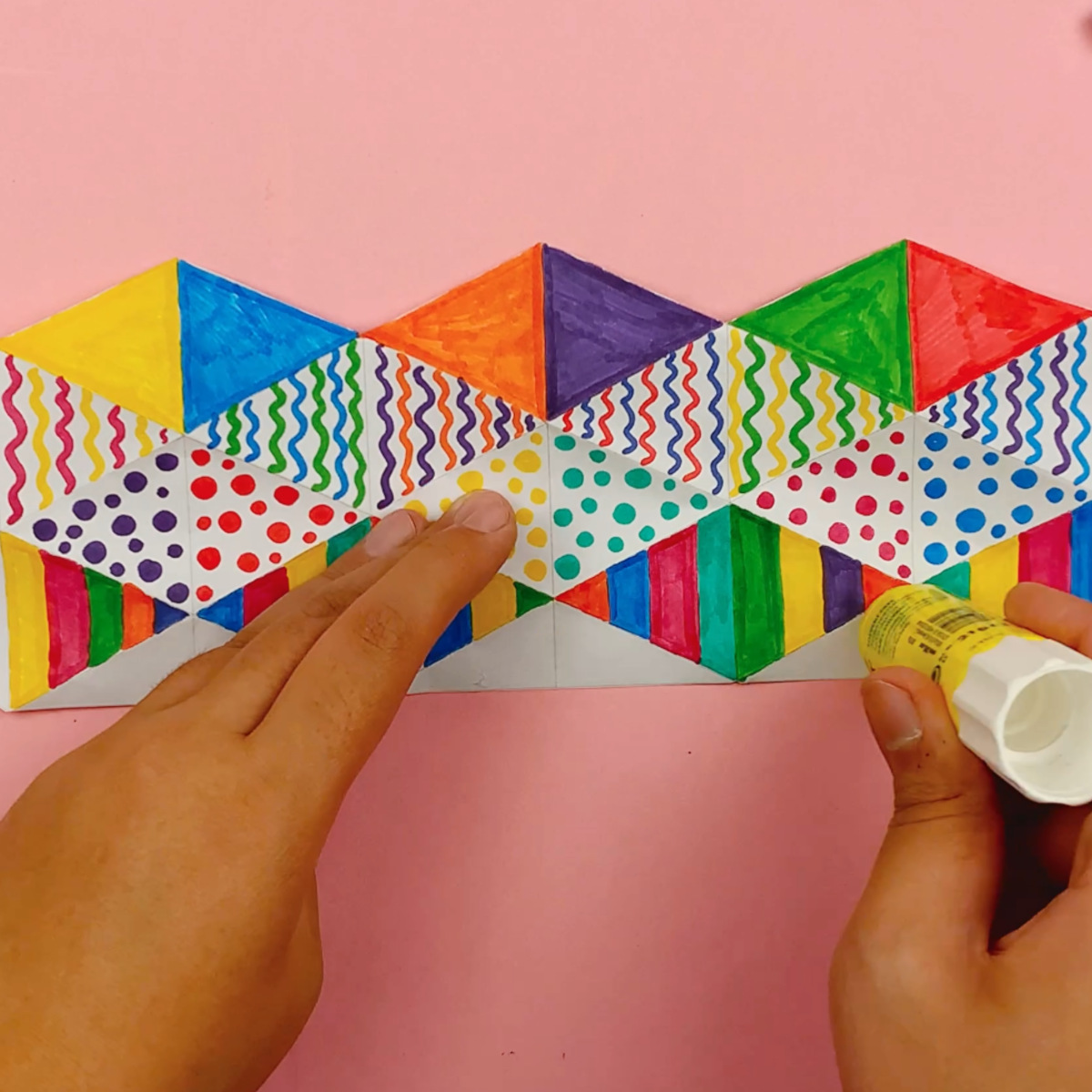Two hands applying glue and forming the flextangle into a tube.