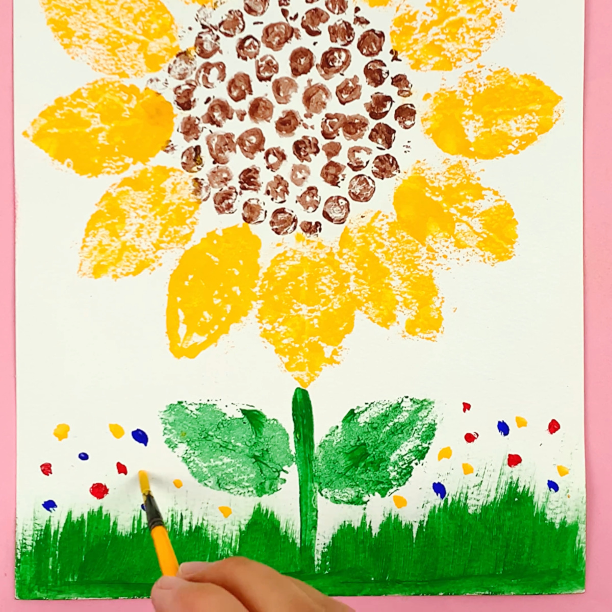 A hand adding more color to the painting using various colored paints. 