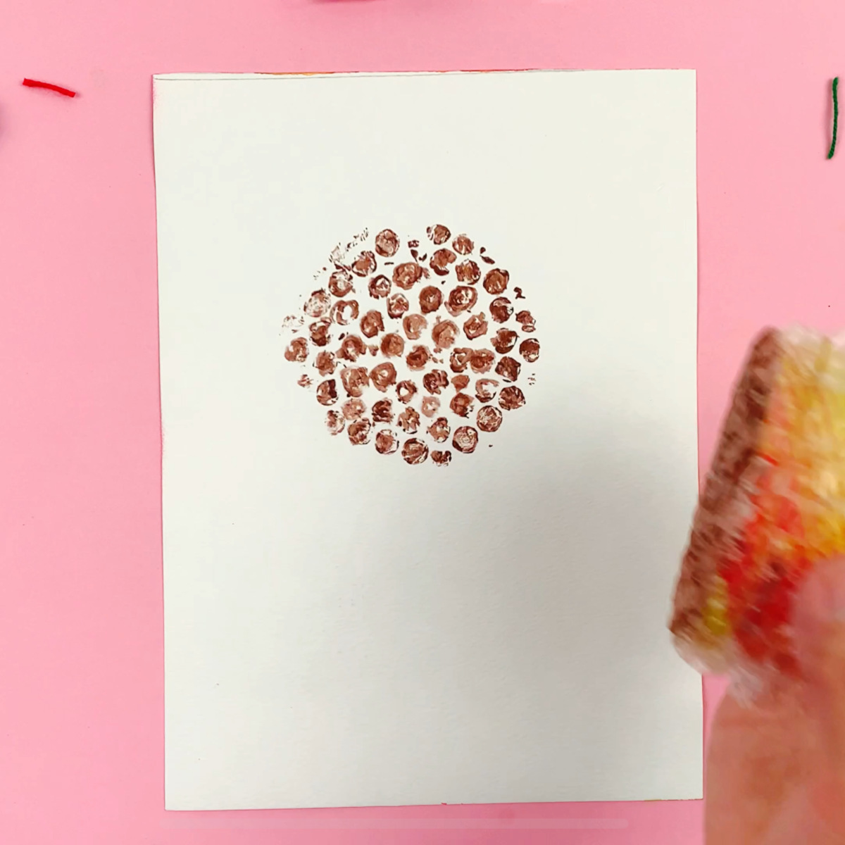 A hand stamping the bubble wrap down to form the flower center.