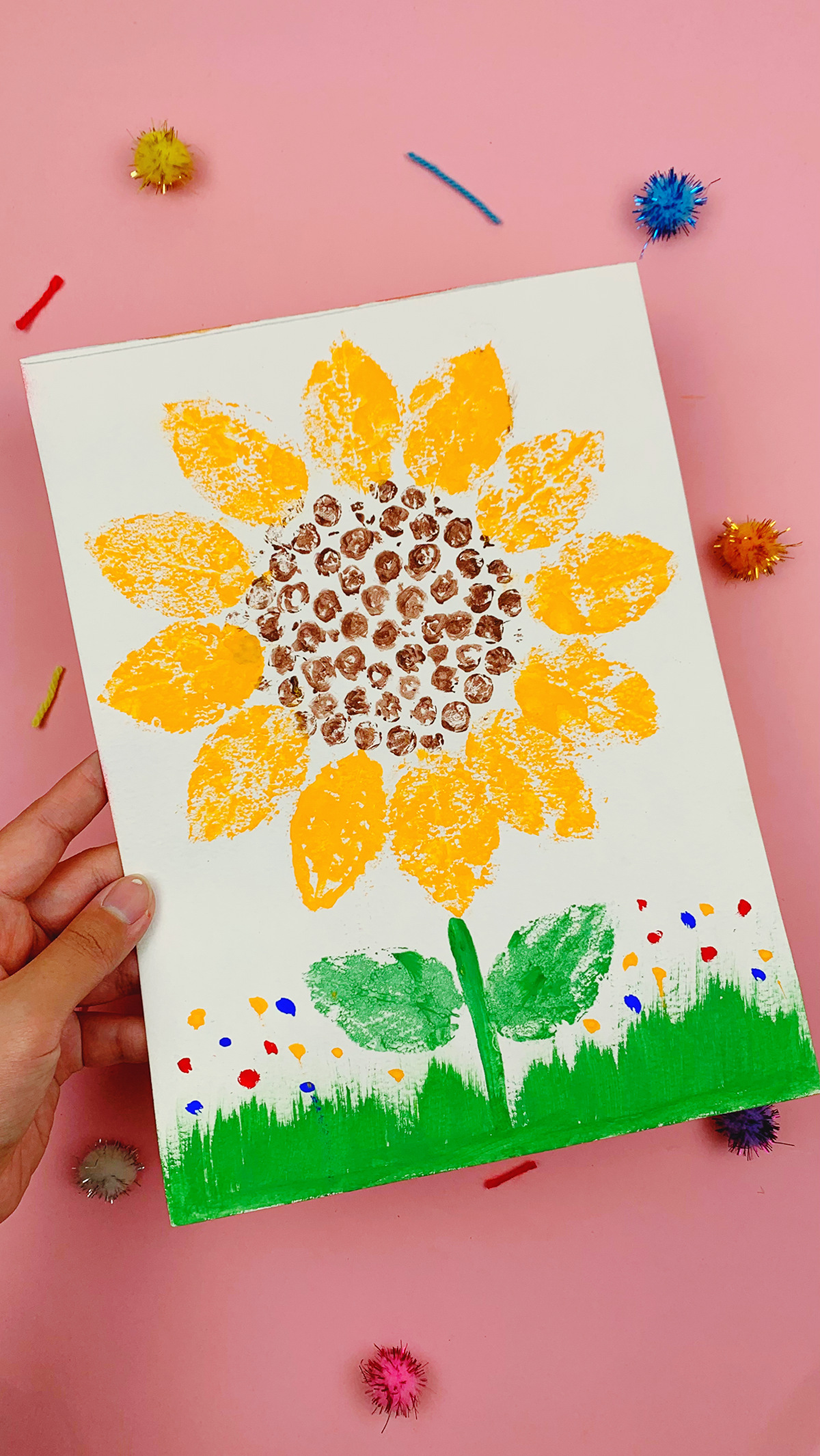 A hand holding the completed bubble wrap sunflower painting.