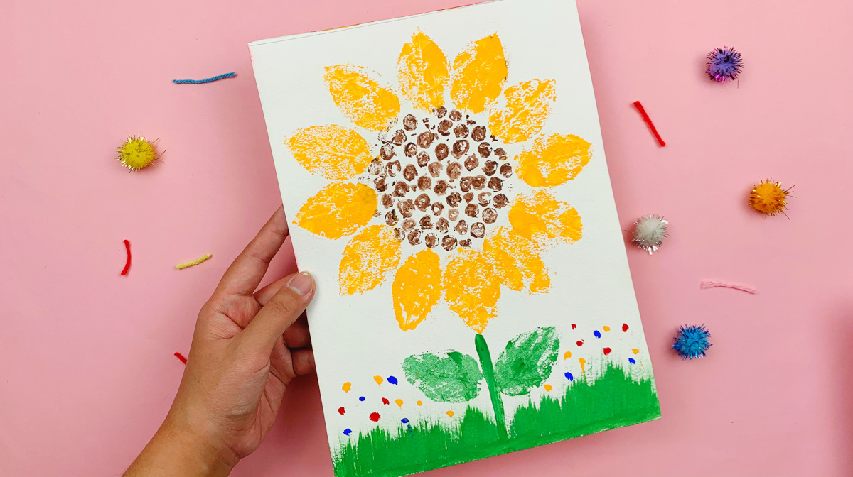 A hand holding a finished bubble wrap sunflower painting made with instructions from Skip to My Lou. 